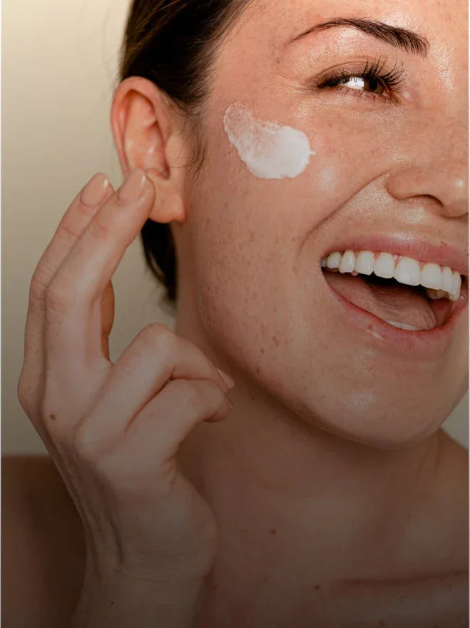 Femme souriante appliquant une crème visage, soin cosmétique et maquillage naturel